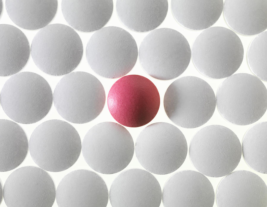 Close up of white pills and one red pill Photograph by Andrew Brookes