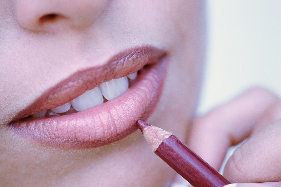 Close-up of woman applying lip liner Photograph by Stockbyte