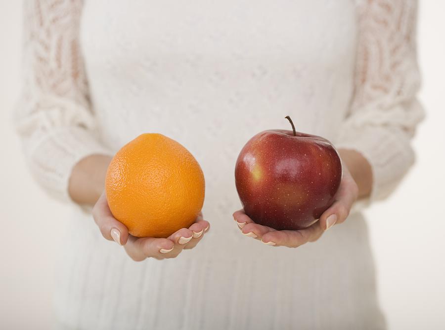 Close up of woman holding apple and orange Photograph by Tetra Images