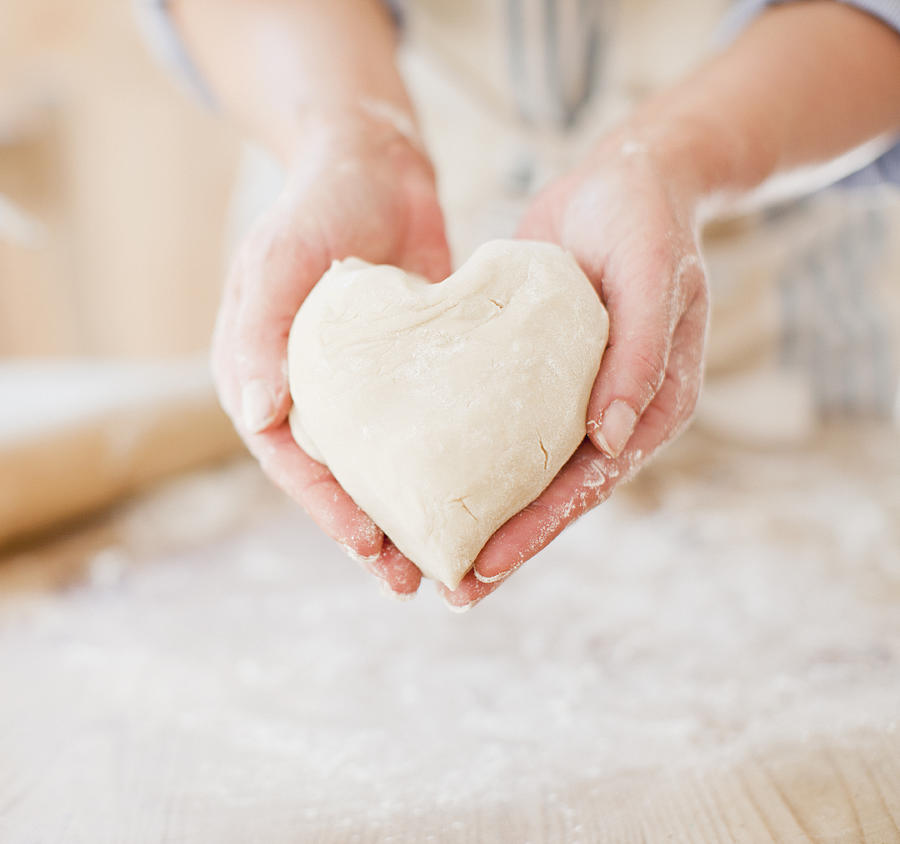 Close up of woman holding heart-shape dough Photograph by Tom Merton