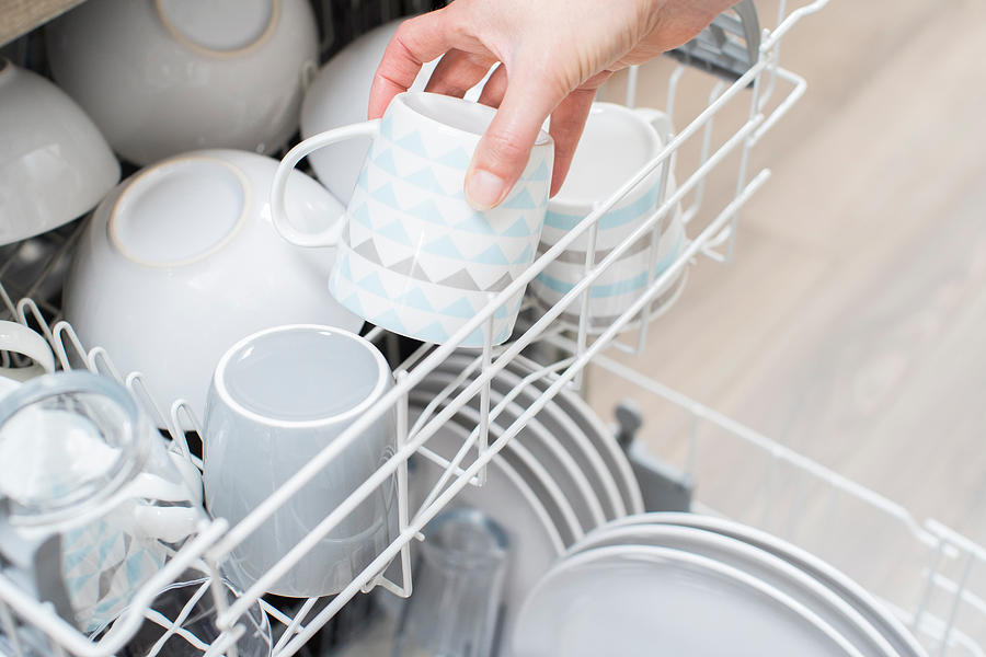Close Up Of Woman Loading Crockery Into Dishwasher Photograph by Daisy-Daisy