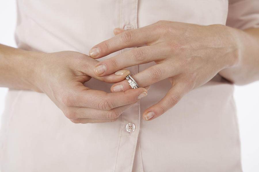 Close-up of woman removing wedding ring from finger Photograph by Vstock LLC