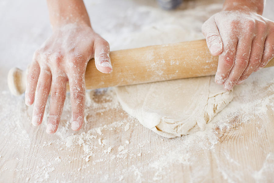 Close up of woman rolling dough with rolling pin Photograph by Tom Merton