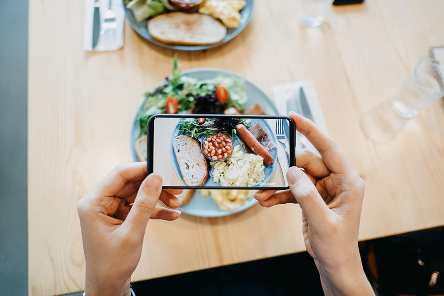 Close up of womans hand taking a photo of fresh breakfast with smartphone Photograph by D3sign