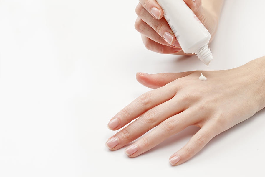 Close up of womans hands applying  moisturizer, studio shot Photograph by Jan Scherders