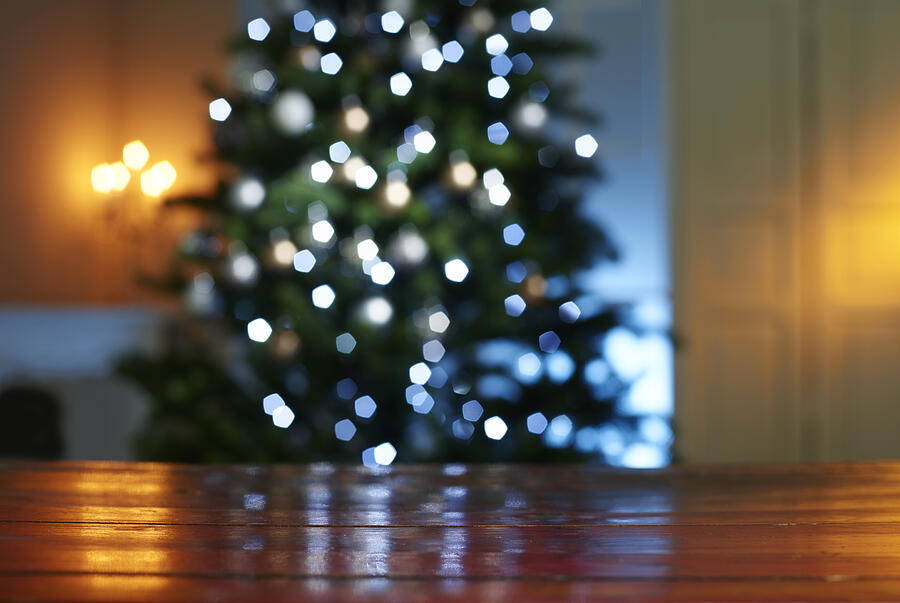 Close-up of wooden table with illuminated Christmas tree in background at home Photograph by Westend61