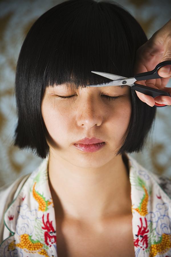 Close up of young Asian woman having bangs trimmed Photograph by Terry Vine