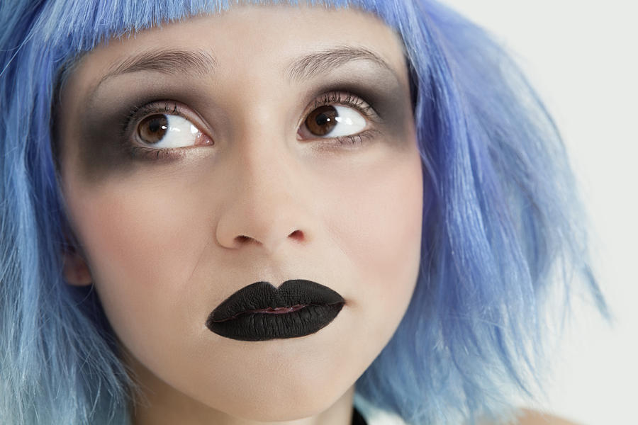 Close-up of young female punk with black lipstick, eye make-up and blue hair Photograph by Moodboard