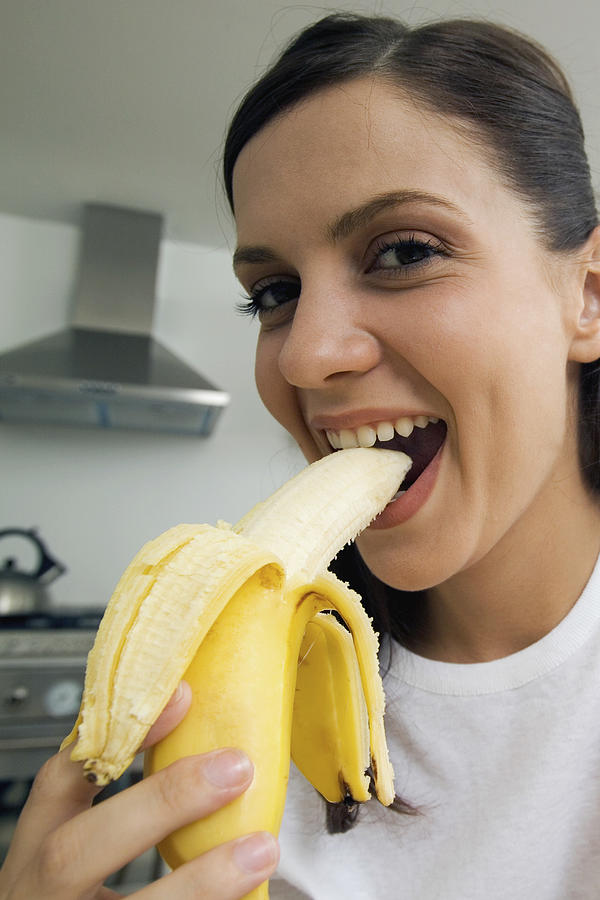 Close-up of young woman eating banana, low angle view, selective focus Photograph by Medioimages/Photodisc