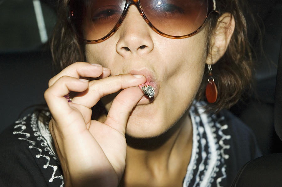 Close-up of young woman in sunglasses smoking a marijuana joint Photograph by Medioimages/Photodisc