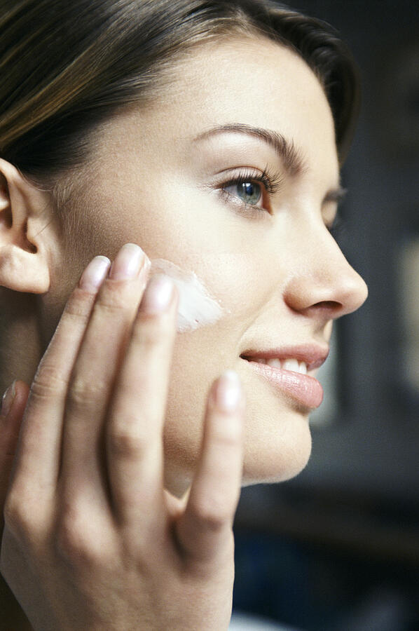 Close-Up Profile of a Young Woman Applying Moisturizer to Her Face Photograph by Hill Creek Pictures