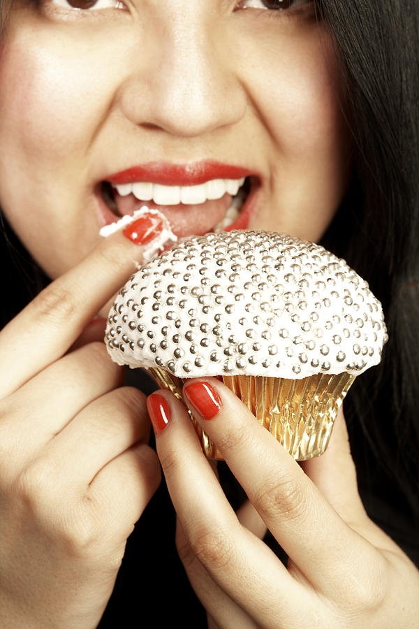 Close-up shot of a young lady tasting the icing of a jewelled cupcake Photograph by Tina Chang