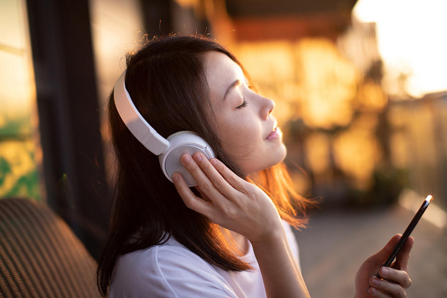 Close-up Shot Of Young Woman Enjoying Music Over Headphones And Using Smart Phone Photograph by Oscar Wong