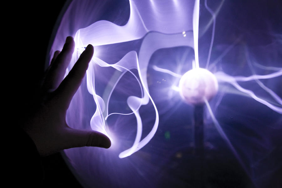 Closeup of a hand touching a plasma lamp. Photograph by Jim Foley