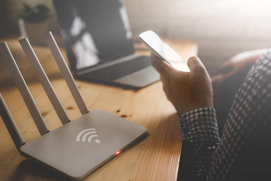 Closeup Of A Wireless Router And A Man Using Smartphone On Living Room At Home Ofiice Photograph by Casezy