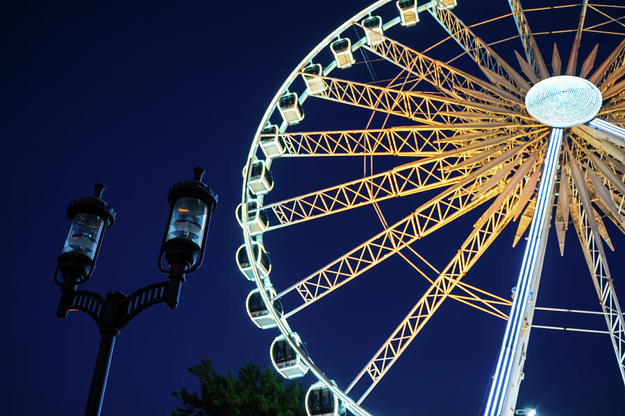 Closeup view of european style street lamp and illuminated ferries wheel behind it during night time located in old town over motlawa river Photograph by Arpan Bhatia