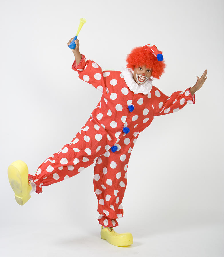 Clown holding horn, standing on one leg, portrait Photograph by Sheer Photo, Inc