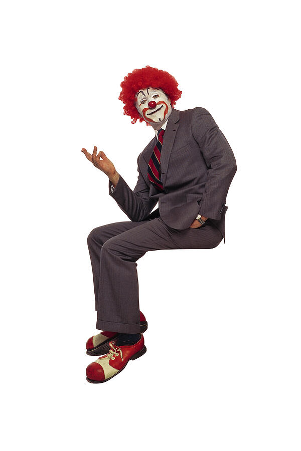 Clown in business suit sitting on ledge Photograph by Comstock