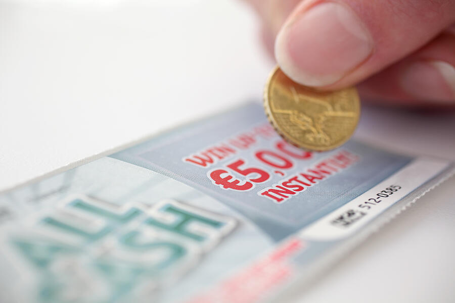 Coin scratching a lottery scratch card Photograph by Daniel Allan