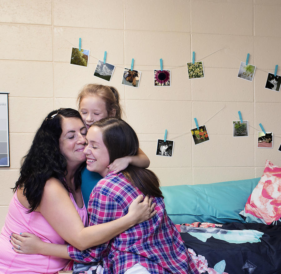 College student hugging family in dormitory room Photograph by Hill Street Studios