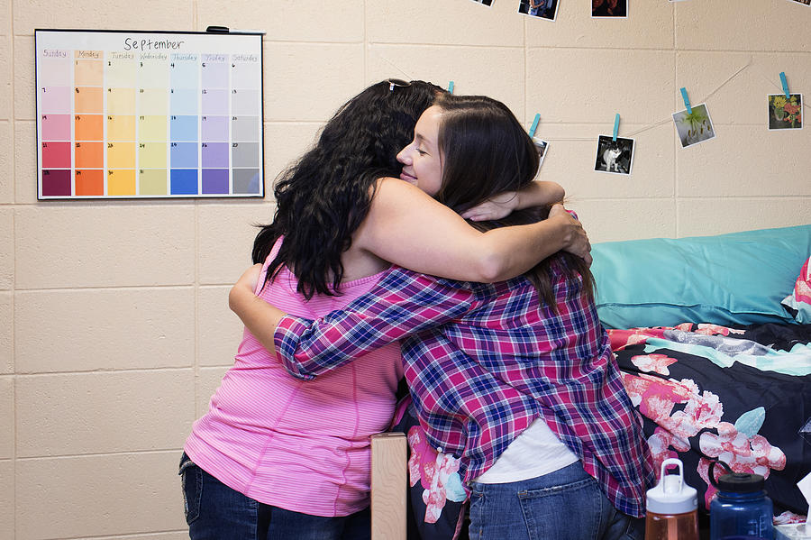College student hugging mother in dormitory room Photograph by Hill Street Studios