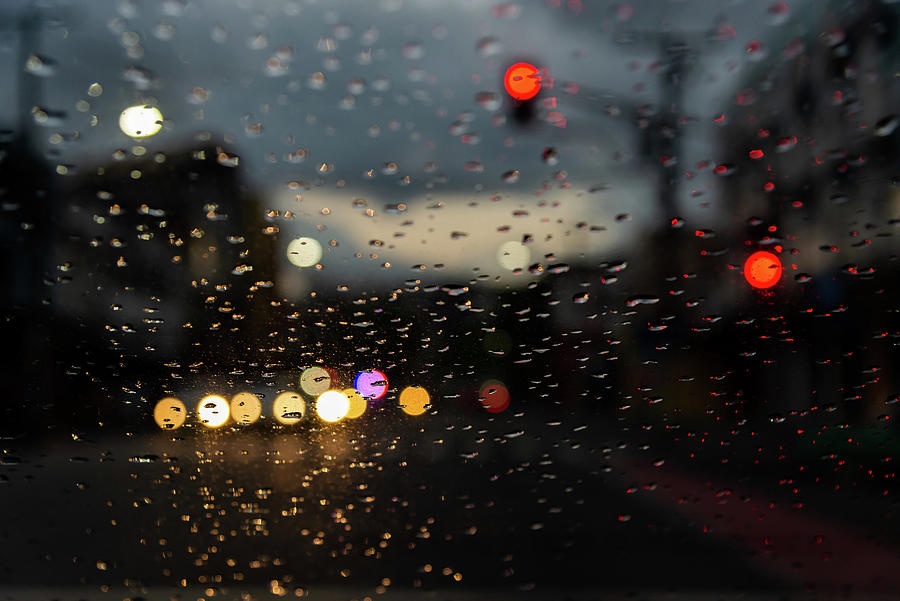 Colored lights blur through the car window, wet with raindrops ...