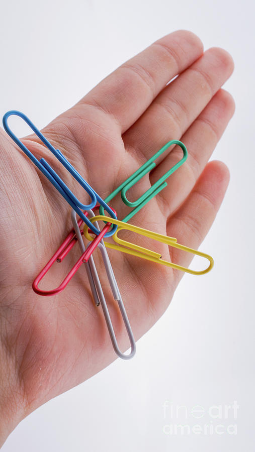 Colorful clips placed in a hand on white background Photograph by