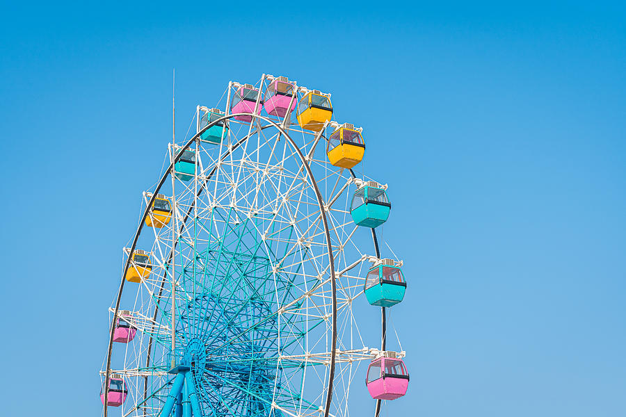 Colorful ferris wheel in an amusement park against blue sky Photograph by Sen Li