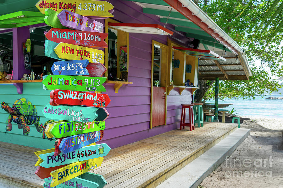 Colorful travel direction signs and beach bar Photograph by Delphimages Photo Creations