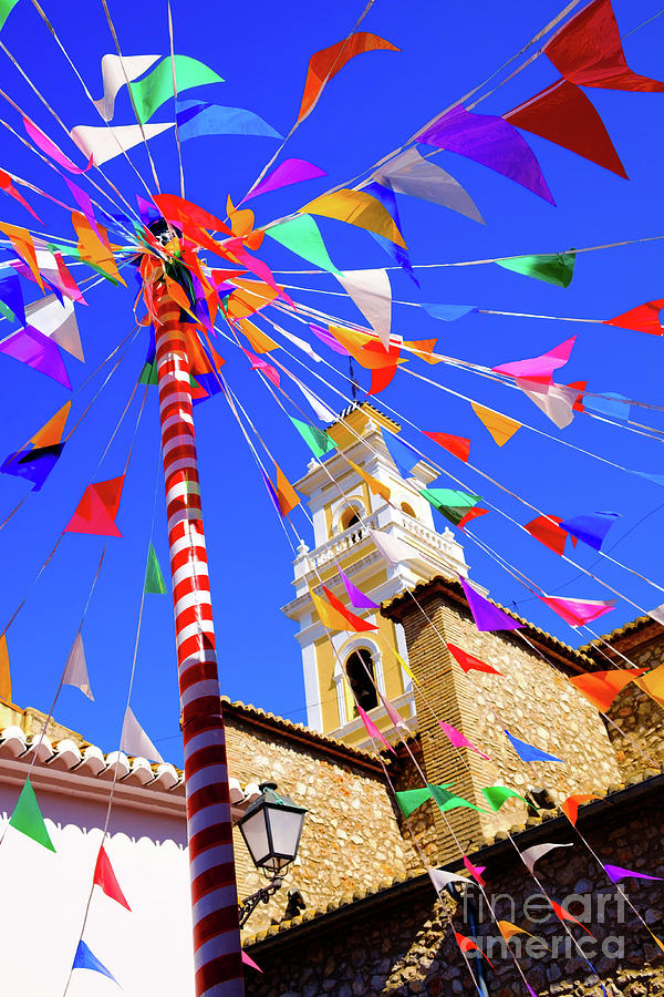 colourful bunting and fiesta pole with church tower in Spanish v Photograph by Peter Noyce