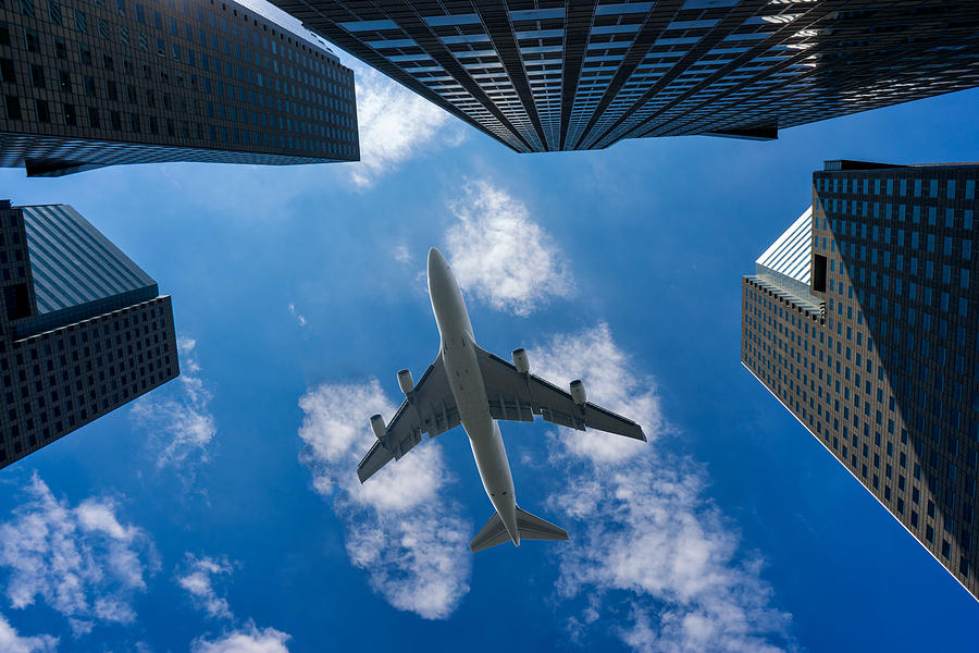 Commercial airplane flying over modern building Photograph by Mongkol Chuewong