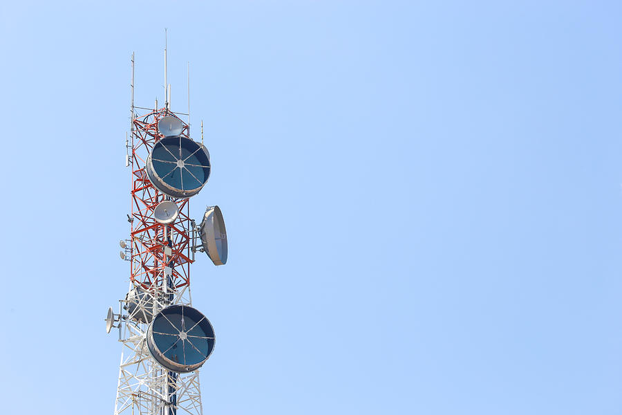 Communication tower over blue sky. Photograph by Istocksupasit