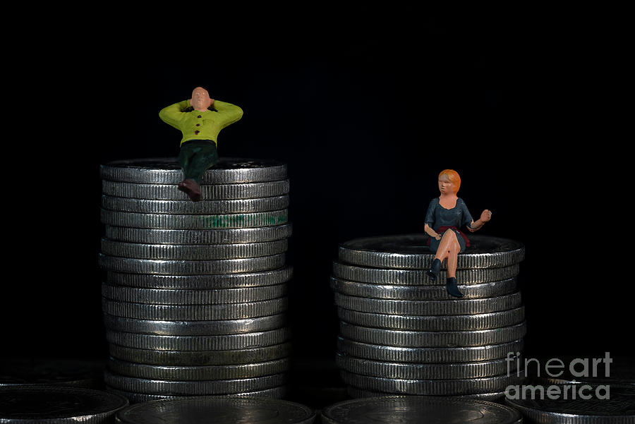 Concept of gender discrimination in remuneration. A miniature man and a miniature woman on top of a pile of coins. Macro Photograph by Pablo Avanzini