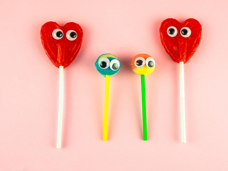 Concept of love and family. Two red heart lollipops with eyes looking at each other and two smaller lollipops Photograph by Ana Maria Serrano