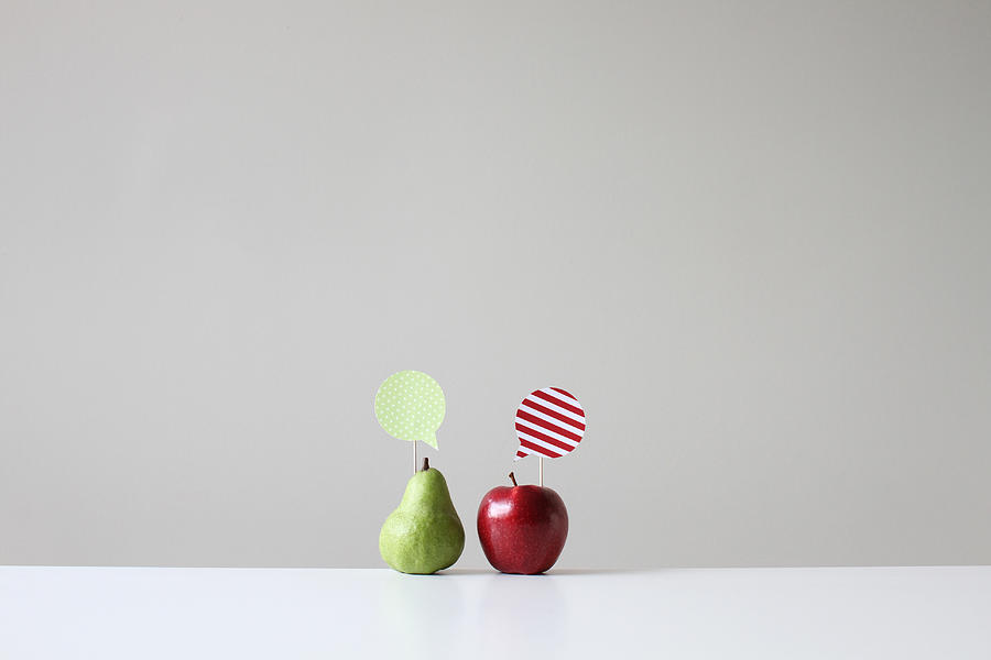 Conceptual apple and pear with speech bubbles Photograph by Pchyburrs