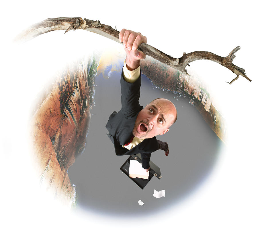 Conceptual Caricature Of A Caucasian Business Man In A Suit As He Hangs From A Branch Over A Large Canyon Photograph by Photodisc