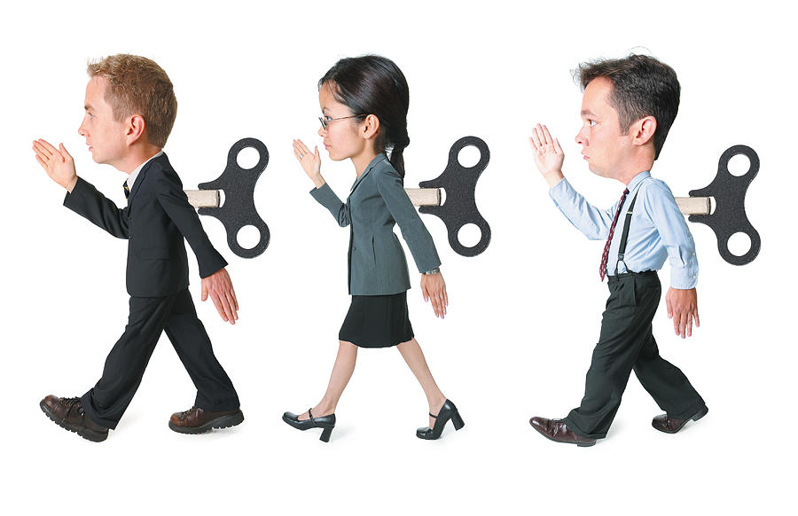 Conceptual Caricature Of A Three Business People With Wind Up Cranks In The Backs March Forward In The Same Way Photograph by Photodisc