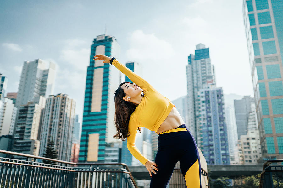 Confidence and determined sports woman stretching arms outdoors against urban cityscape Photograph by AsiaVision