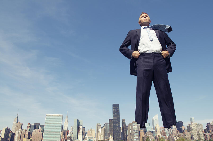 Confident Giant Businessman Standing Tall Over City Skyline Photograph by PeskyMonkey