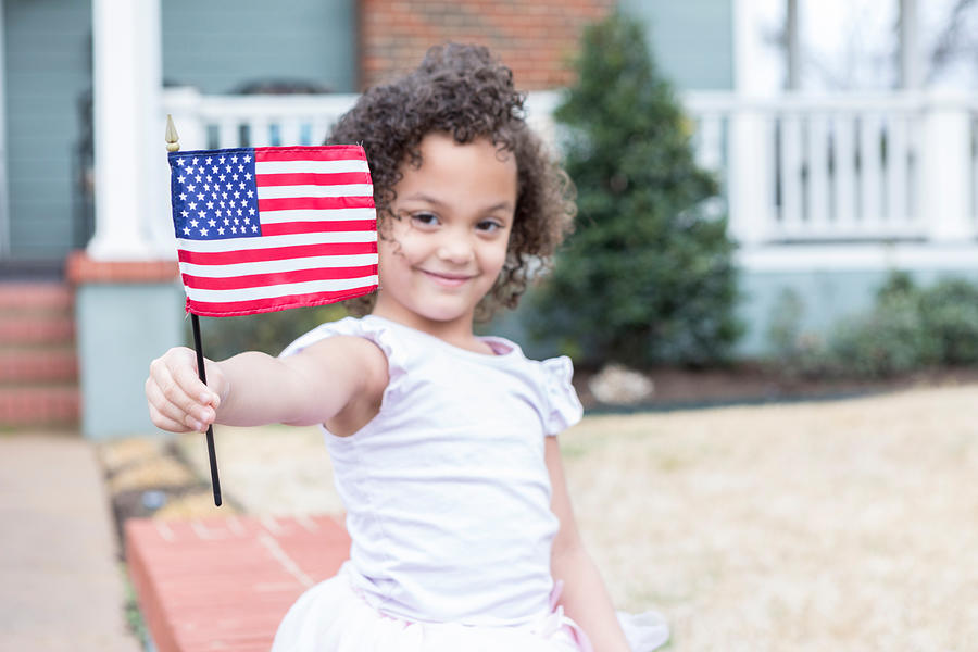 Confident little girl in front yard with American flag Photograph by SDI Productions