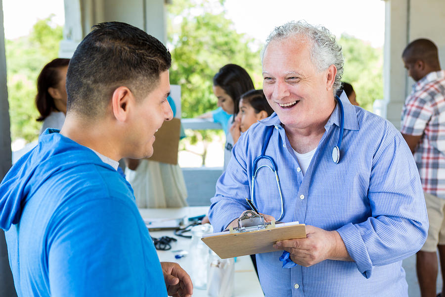 Confident senior doctor talks with patient at free outdoor clinic Photograph by SDI Productions
