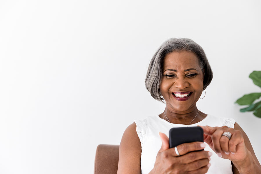 Confident woman laughs while using smartphone Photograph by SDI Productions