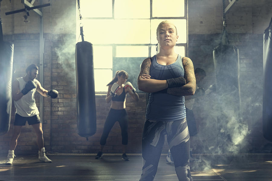 Confident woman posing near punching bags in gymnasium Photograph by Colin Anderson Productions pty ltd