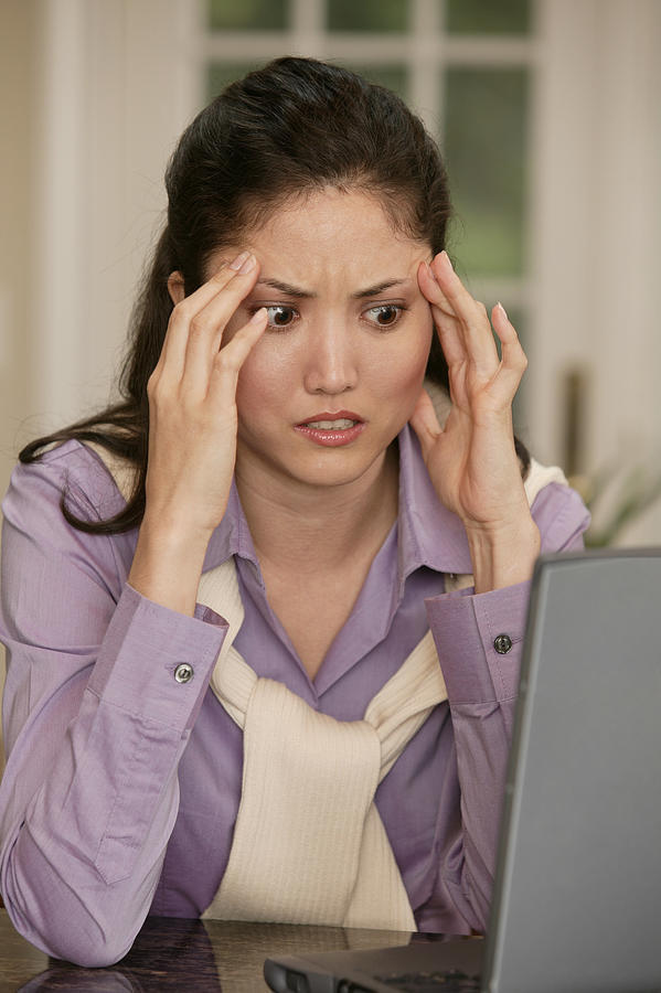 Confused woman using laptop Photograph by Comstock Images