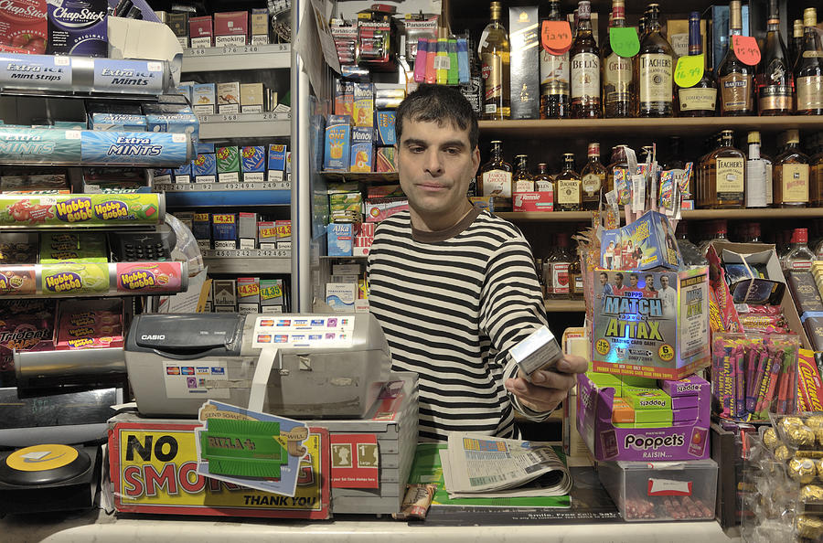 Convenience store owner handing over cigarettes. Photograph by Jac Depczyk