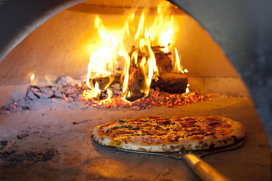 Cooked pizza coming out of hot brick oven Photograph by Lisa Romerein