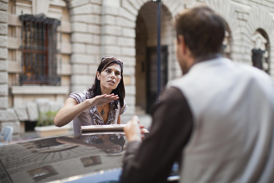 Couple arguing over sports car Photograph by Hybrid Images