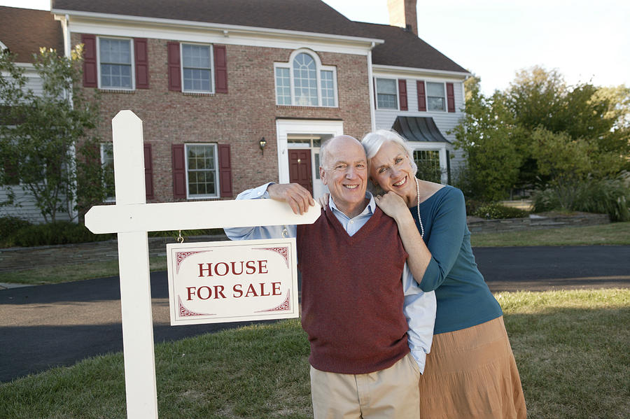 Couple by real estate sign Photograph by Comstock Images