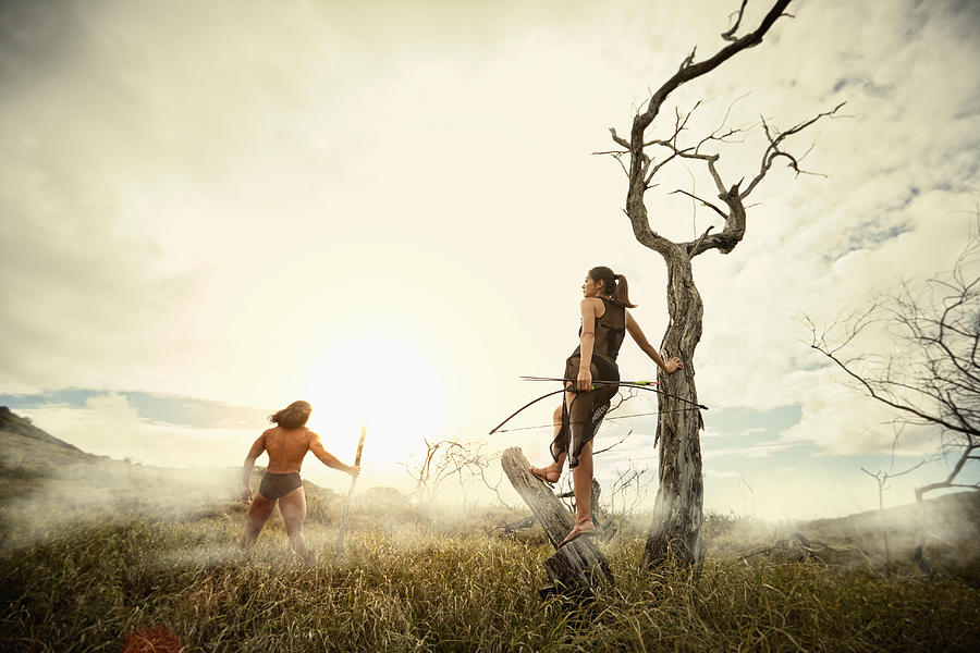Couple carrying bows and arrows in foggy field Photograph by Colin Anderson Productions pty ltd