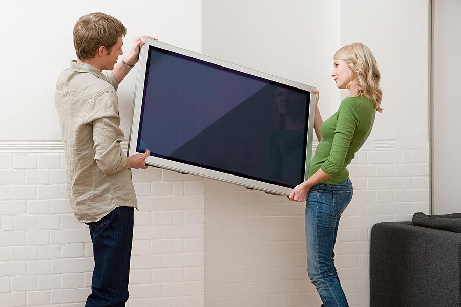Couple carrying plasma screen television Photograph by Image Source